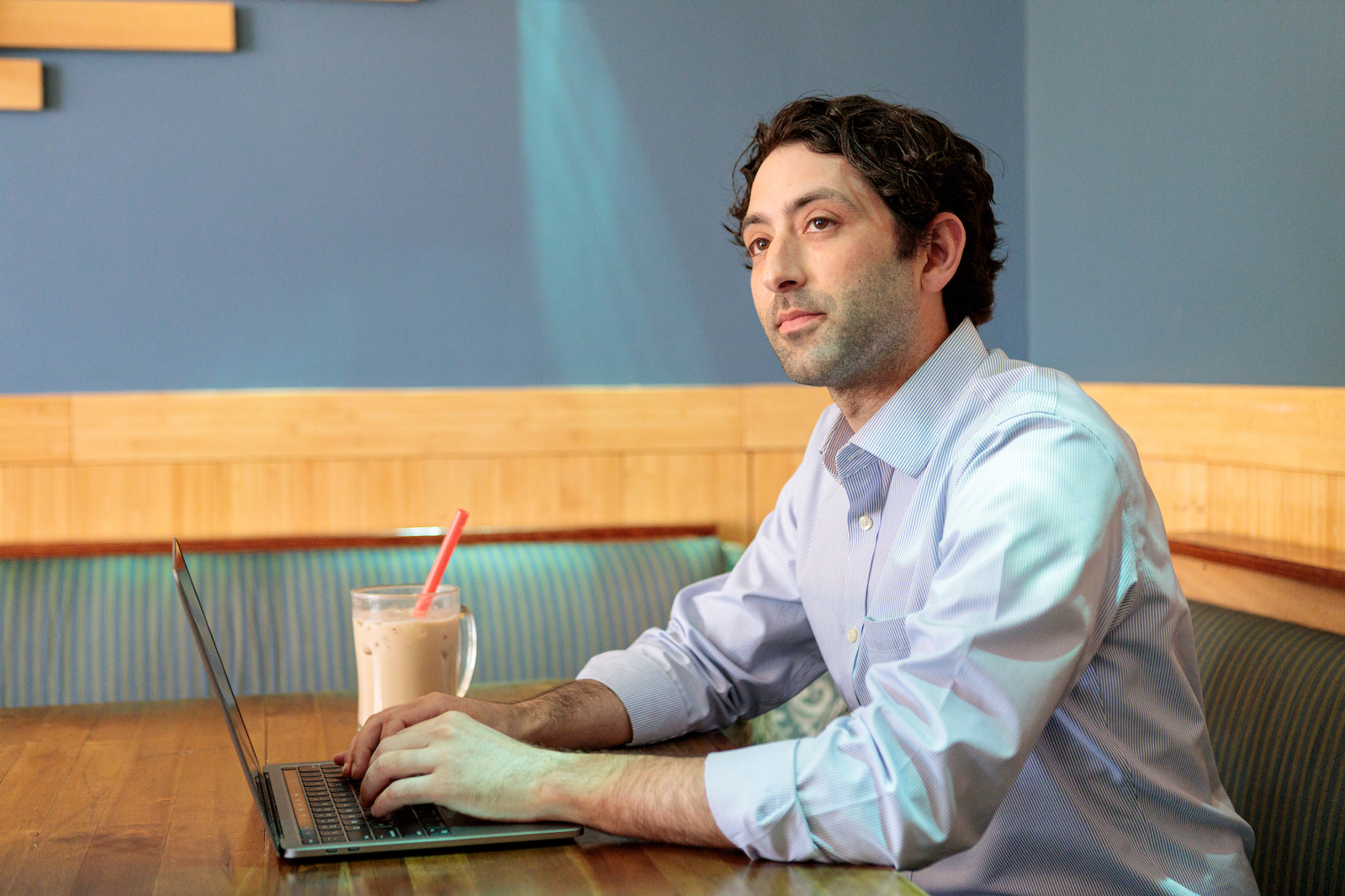 Business student sitting in a cafe doing course work on his laptop