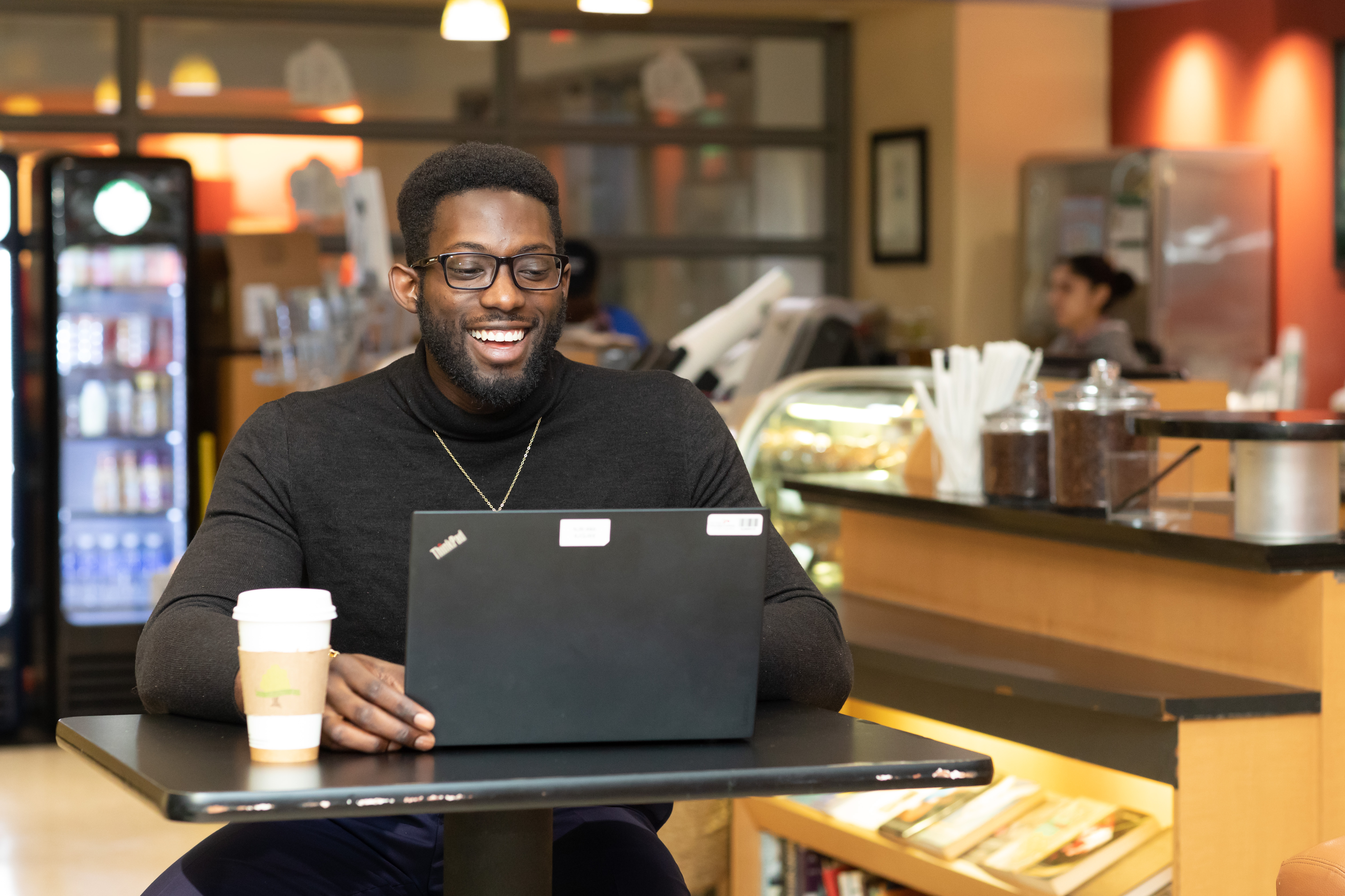 Black male graduate student sitting in a cafe at his laptop