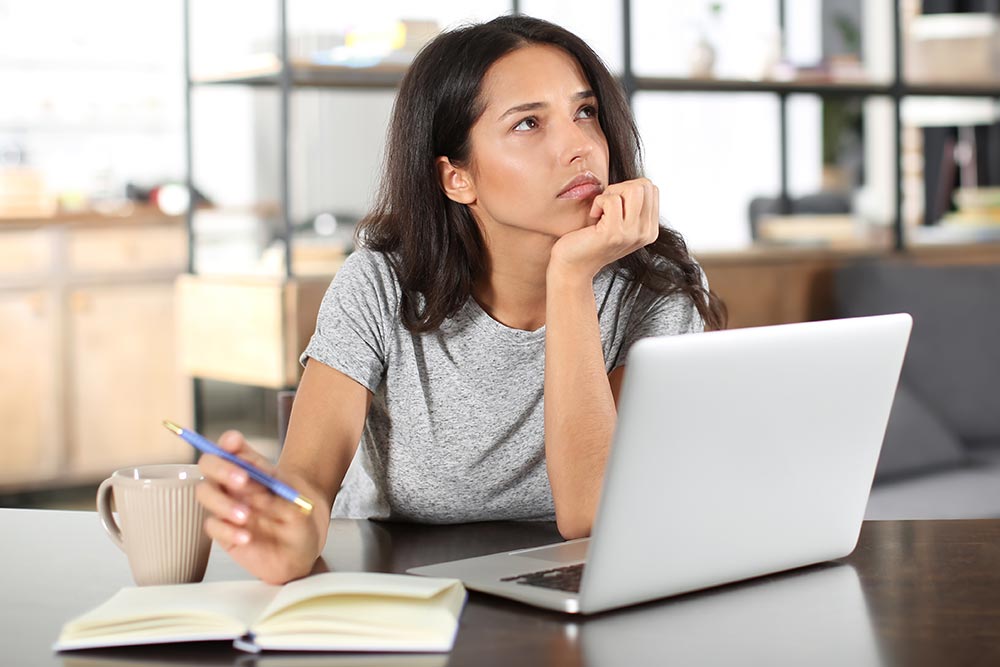 a student working at laptop pondering further education.