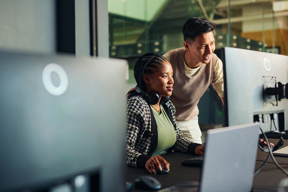 Two artificial intelligence professionals at a computer collaborating on a project.
