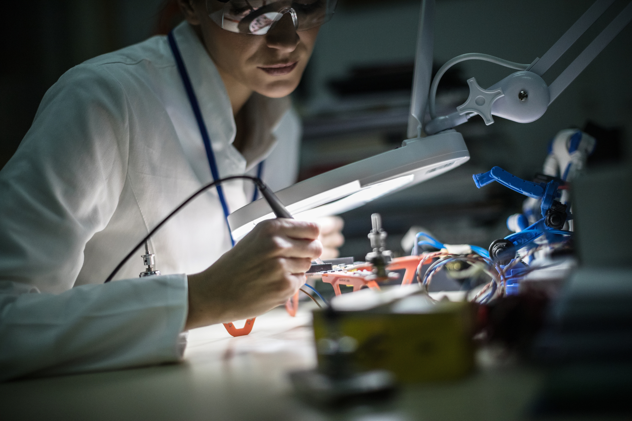 Female electrical engineer working on a project at her desk with wires 