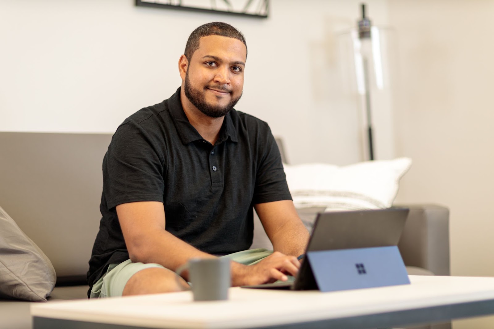 Male employee working from home on his couch with his laptop open on the coffee table