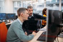 Two cybersecurity professionals reviewing information on a computer screen in an office setting
