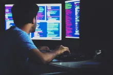 Big Data professional sitting in front of a computer monitor looking at data