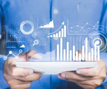 Hands holding a tablet projecting data and charts above it