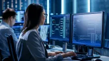 Female cybersecurity professional sitting at a computer working on coding
