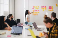 Group of young professionals in a meeting room going over notes on a whiteboard