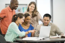 Group of graduate students working together in front of a desktop