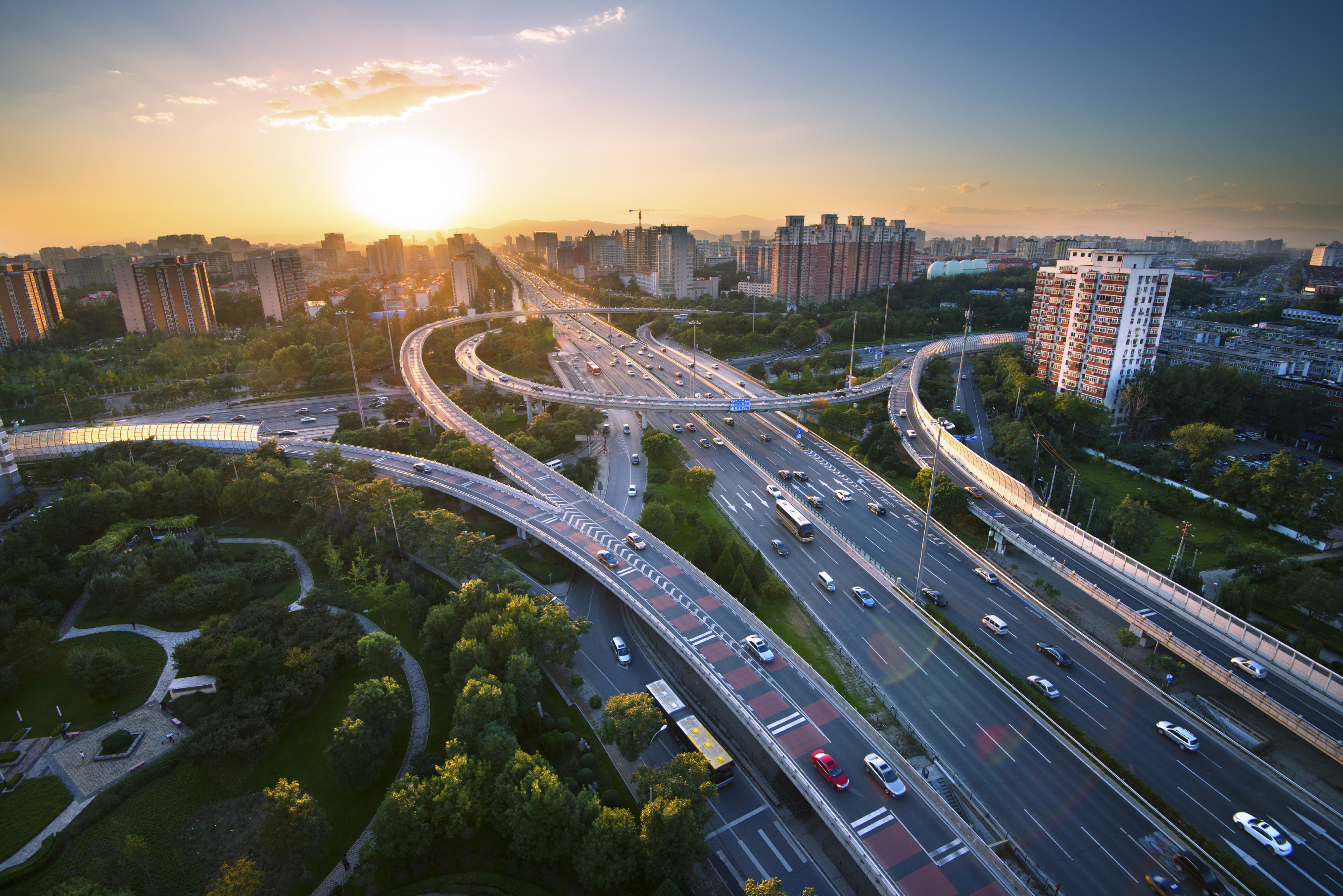 Complex highway with cars driving and a skyline of a city behind it